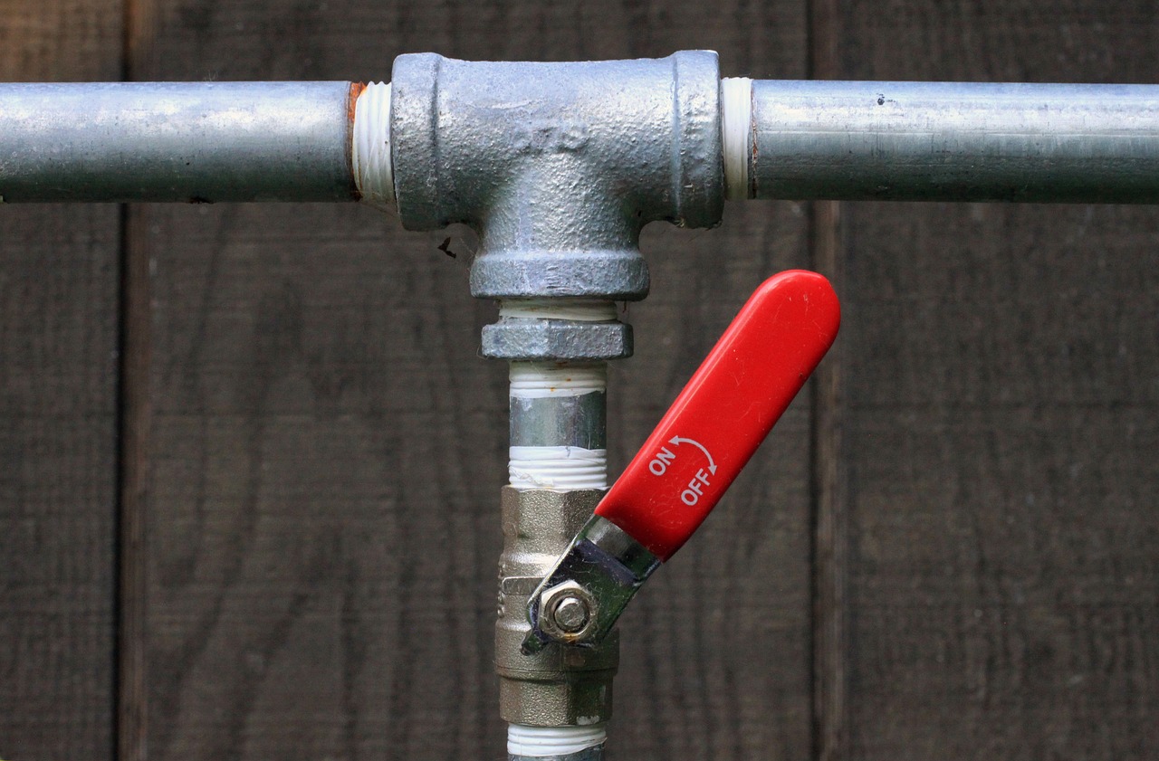 Image of a leaking pipe with a red valve, representing pipe repair services.