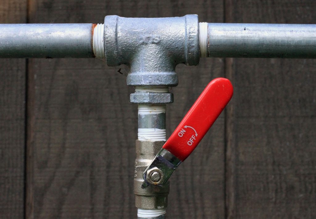 Image of a leaking pipe with a red valve, representing pipe repair services.